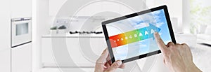 Energy efficiency concept hand touch digital tablet with colored symbols on blue sky, isolated on blurred kitchen background web