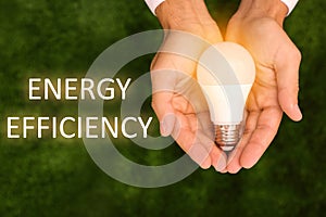 Energy efficiency concept. Man holding lamp bulb against green background