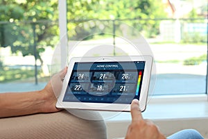 Energy efficiency home control system. Man using tablet to set temperature in different rooms