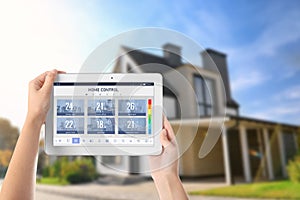 Energy efficiency home control system. Woman using tablet to set temperature in different rooms