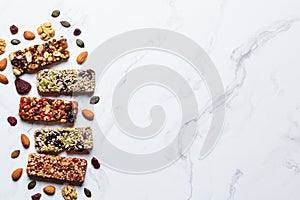 Energy granola bars with different seeds, nuts and dried fruits and berries on white marble background. Healthy snack concept