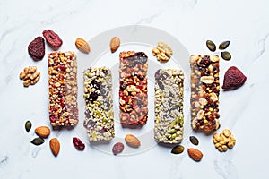 Energy granola bars with different seeds, nuts and dried fruits and berries on white marble background. Healthy snack concept