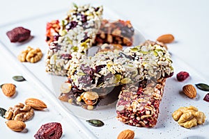 Energy granola bars with different seeds, nuts and dried fruits and berries on white marble background. Healthy snack concept