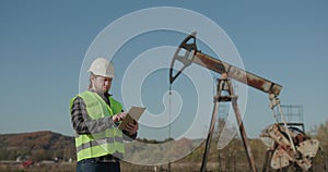 Energy Industry Business Man Holding Device Using Digital Tablet Oil Pump Field. Pumpjack Technician Man Working Digital