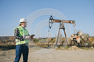 Energy Industry Business Man Holding Device Using Digital Tablet Oil Pump Field. Pumpjack Technician Man Working Digital