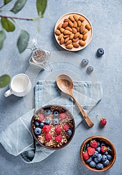 Energy muesli with raspberry,  blueberry, chia seeds, almond nuts and  milk into coconut bowl on blue background