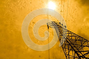 Energy power concept: high voltage pylons with cloud and sun background.