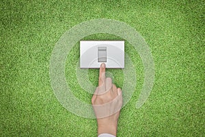 Energy saving and ecological friendly concept with hand turning off switch on green grass lawn