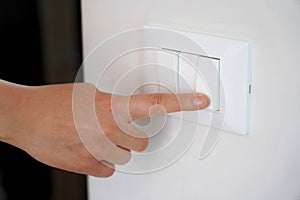 Energy saving. Female finger is turn off on lighting switch