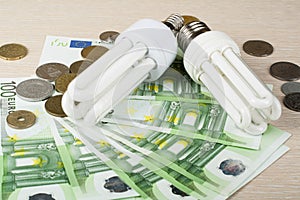 Energy saving fluorescent lamp on money background, Eco light bulb, comparison of energy saving lamps and incandescent