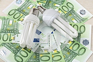 Energy saving fluorescent lamp on money background, Eco light bulb, comparison of energy saving lamps and incandescent