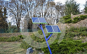 Energy saving installation - solar panels in the park among the trees green foliage background