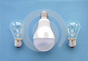 Energy-saving lamp with incandescent lamps in a row on a blue background. The concept of saving energy