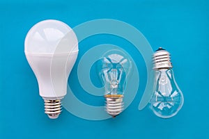Energy-saving lamp with incandescent lamps in a row on a blue background. The concept of saving energy