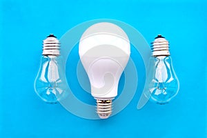 Energy-saving lamp with incandescent lamps in a row on a blue background. The concept of saving energy