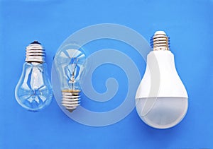 Energy-saving lamp with incandescent lamps in a row on a blue background. The concept of saving energy