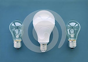 Energy-saving lamp with incandescent lamps in a row on a blue background. The concept of saving energy