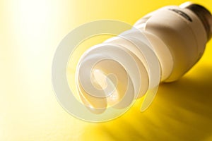 Energy saving lamp on yellow background. Close up. The concept o