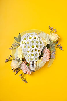 Energy Saving LED Lamp with Flowers over yellow background. Gree