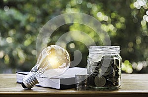 Energy saving light bulb with coins in glass jar for saving, financial and accounting concept and copy space for insert text