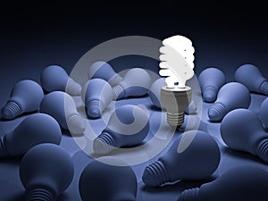 Energy saving light bulb , one glowing compact fluorescent lightbulb standing out from unlit incandescent bulbs on blue photo