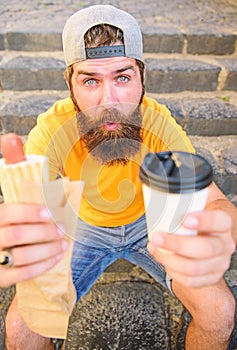 Energy from street food make significant contribution to diet. Man bearded enjoy quick lunch stairs background. Hipster