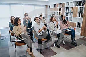 Engaged audience applauding speaker or trainer at business workshop in modern office.