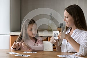 Engaged caring mother helping little daughter with learning math