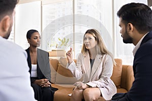 Engaged Caucasian business woman talking to multiethnic colleagues