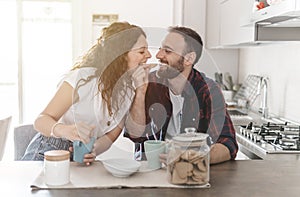 Engaged couple has breakfast together in their new home - young couple jokes while eating cookies - love and well-being concept -