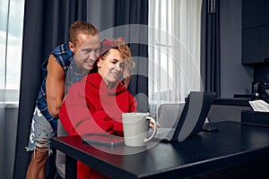 Engaged couple has breakfast together in their new home - young couple smiling and hugging while drinking and eating in