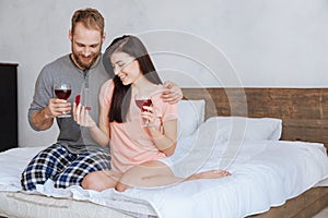 Engaged couple looking at diamond ring and drinking wine