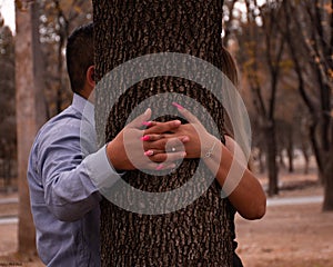 Engaged couple in photo session, kiss behind the tree