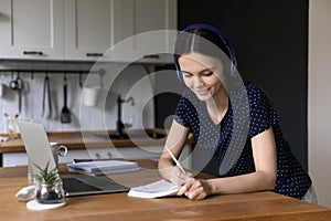 Engaged happy millennial college student girl writing notes at laptop