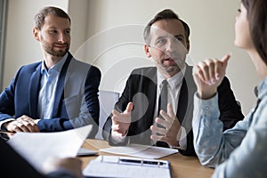 Engaged mature business leader man talking to younger colleague