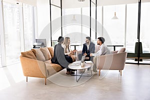 Engaged multiethnic business team sitting in circle on couch