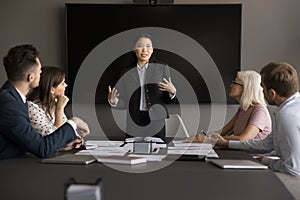 Engaged young Asian project manager presenting startup to coworkers