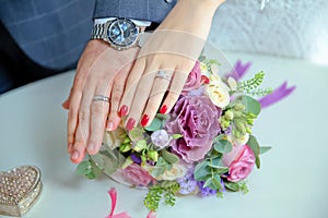Engagement flowers .The girl and the boy put their hands on colorfull roses. Bride and groom with Engagement gold rings put their