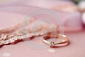 Engagement ring closeup with a diamond on a pink background. Eternal love concept. Valentine`s day proposal