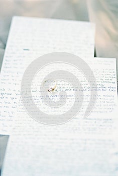 Engagement ring lies on handwritten wedding vows on sheets of paper