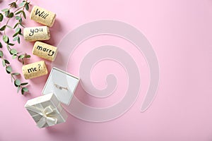 Engagement ring and text WILL YOU MARRY ME? on color background