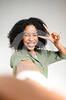 Engaging directly with the camera, an African-American woman makes a peace sign with her fingers