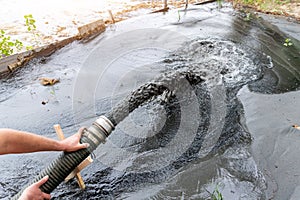 Engeneer hold pipe of power pump machine pouring mud sludge waste water with sand silt on ground. Sand-wash and coast-depeening.