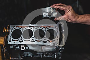 Engine cylinder in the hands of a mechanic. Car engine repair in the garage