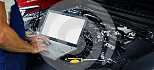 engine diagnostics - car mechanic using laptop computer to diagnose vehicle motor in repair shop. blank screen