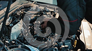 Engine Mechanic Adjusting Car Part, Focused Technician at Work. A skilled engine mechanic adjusts a car part with a
