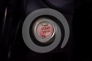 Engine start button of car with a orange light.