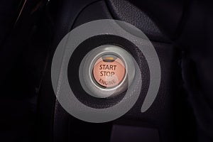 Engine start button of car with a orange light.