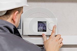 Engineer adjusting thermostat for efficient automated heating system