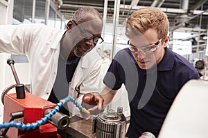 Engineer advising apprentice in factory, front view close up